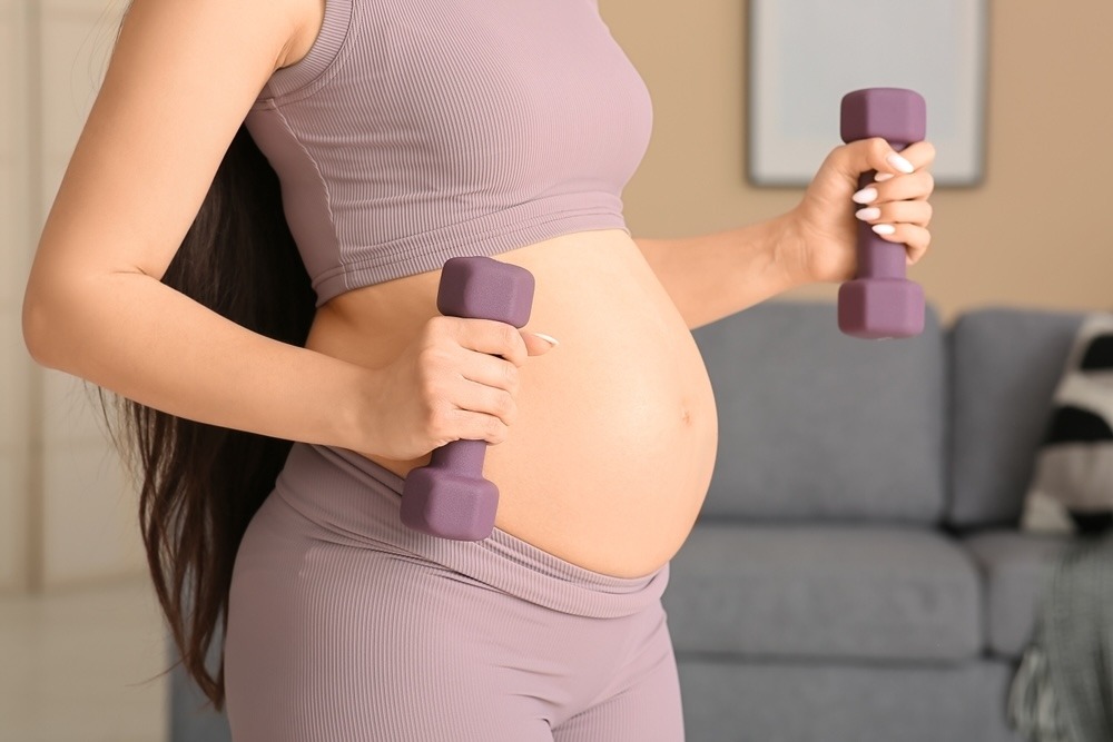 A pregnant woman with weights in her hand.