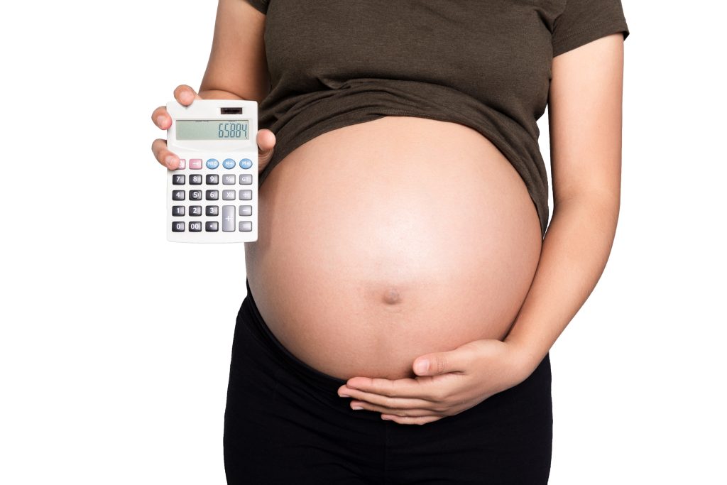 A woman holder her belly and a calculator.